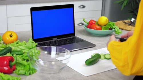 Blue Screen Laptop Woman Housewife in Kitchen Tells Listen Chef Slices Cucumber