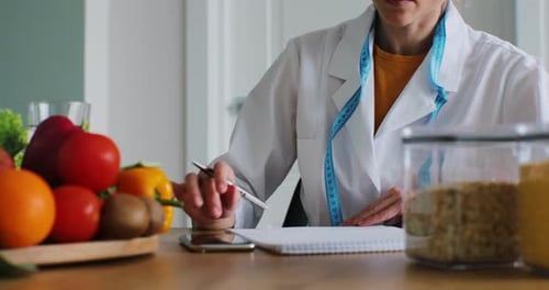 Female Nutritionist Sits Down Notes and Benefits of Tomatoes and Broccoli for Her Patient Meal Plan