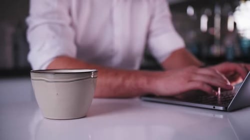 young man works at a laptop and drinks coffee