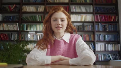 Young Woman Talks in front of Library Bookshelves
