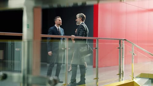 Male Colleagues in Formal Clothing Talking in Office Lobby While Businesswomen Walking Around