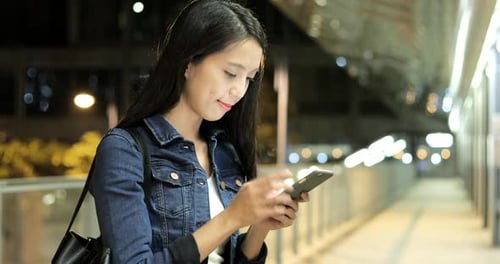 Smiling Woman Using Smartphone at Night in City