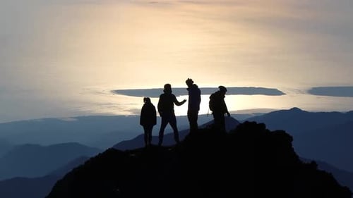 Silhoute of friends taking in the view after climbing a mountain