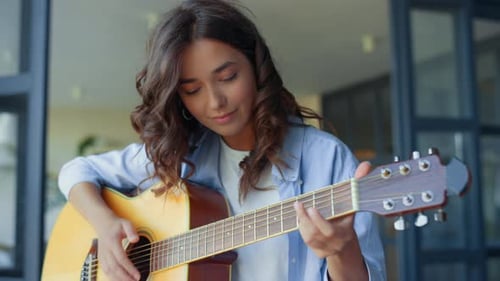 Woman Plays Acoustic Guitar and Sings Indoors