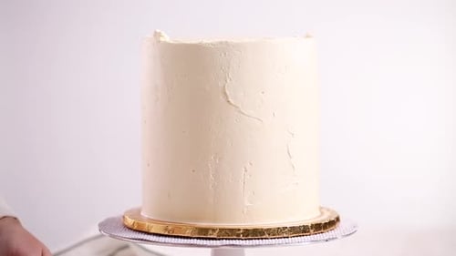 Person Frosting Cake with White Icing