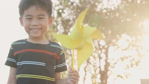 Happiness little boy smiling in wheat field holding small wind wheel or windmill toy