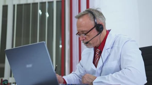 Mann mit Videoanruf mit Patient. Arzt mit Headset gibt Online-Beratung mit Laptop