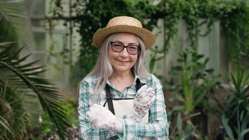 Senior Woman Smiling in Tropical Greenhouse Setting
