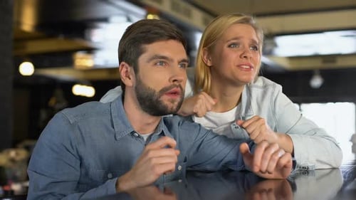 Couple Watches Tense Game Together in Bar Setting