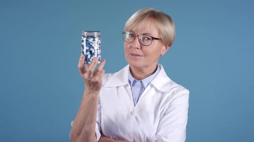 Middle-Aged Female Doctor Holding Bottle of Pills