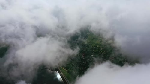 Light clouds moving in the sky. City view from the air through white clouds.