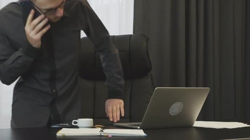 Successful businessman working at modern office talking on phone in front of laptop