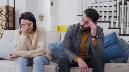 Distressed Couple Sitting Apart on Couch Indoors
