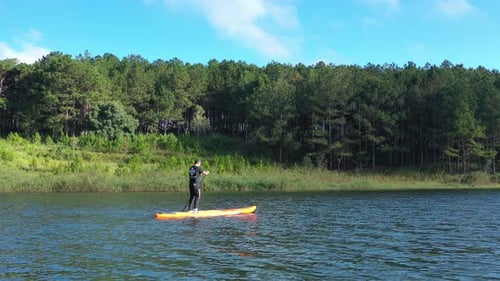 Aerial drone view of man is paddling on stand up paddleboarding in the mountain lakes