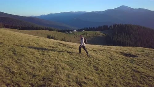 Person Walks on Grassy Hill in Mountains