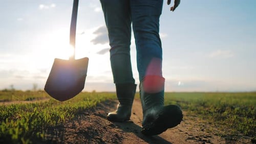 Farmer Walking with Shovel on Rural Path