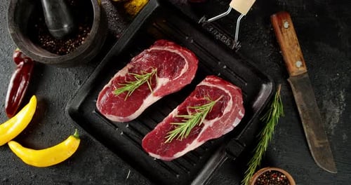 Raw Steaks Seasoned with Rosemary on Grill Pan
