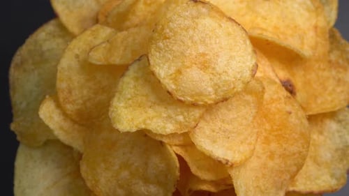 Craft crispy potato chips rotating close up. Golden fried potatoes in macro. Potato snack