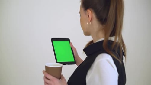 Woman Drinks Coffee Using Tablet With Green Screen