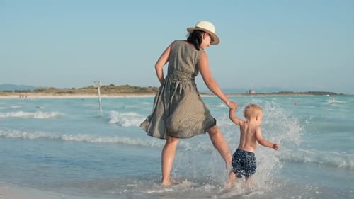 Woman and Child Walking on Beach Shoreline