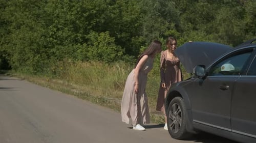 Two Girls in Dresses on Rural Road in Forest Broke Down Car