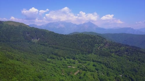 Aerial Drone Flying Over Mountain Valley Overlooking High Peaks and Hills Covered with Green Forest