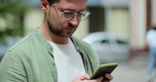 Portrait of Casual Man in Glasses Using Smartphone on the Street