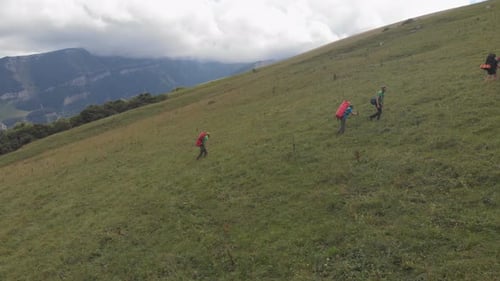 Aerial Shot of a Group of Tourists with Backpacks Climb the Mountain