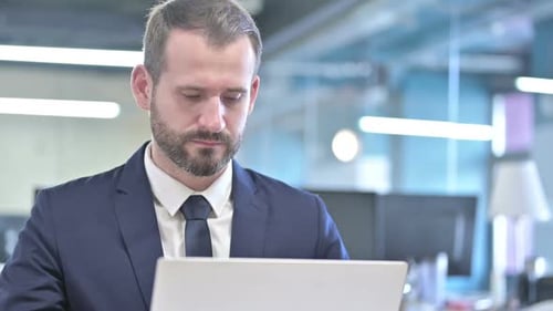 Focused Young Adult Working on Laptop in Office