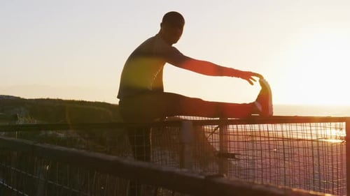 Adult Man Stretching at Sunset on Beach