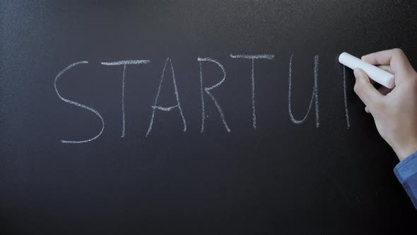 Startup written on chalkboard. Hand writing word Startup with white ...