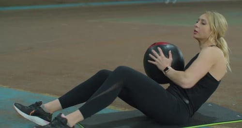 Mujer en ropa deportiva haciendo ejercicios con pelota en el gimnasio