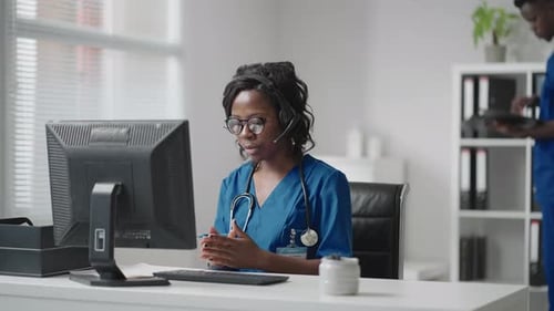 Healthcare Worker Using Computer with Headset in Office