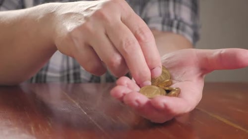 Hands Counting Golden Coins on Wood Table