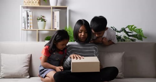 Excited Children Opening Birthday Gift Together Indoors