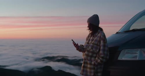 Woman with Phone at Sunrise Above Clouds