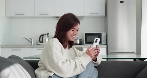 Woman Using Smartphone at Home in Modern Kitchen