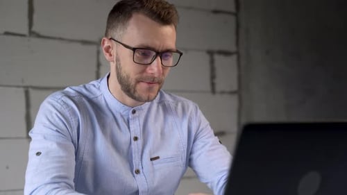 Hübscher Geschäftsmann mit Brille arbeitet am Computer im Büro