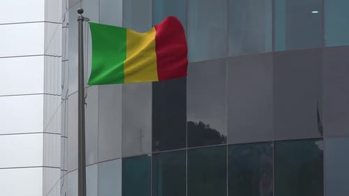 Green Yellow Red Flag Waving on Pole by Modern Building