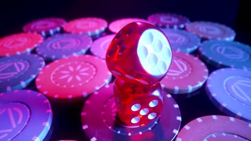 Red Dice Lying on a Pile of Casino Chips Spinning on a Black Background