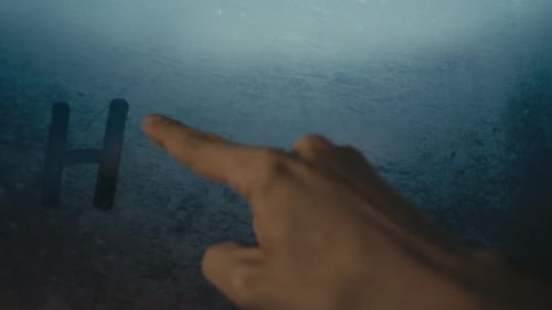 Finger Writes "Help" on Foggy Glass Surface