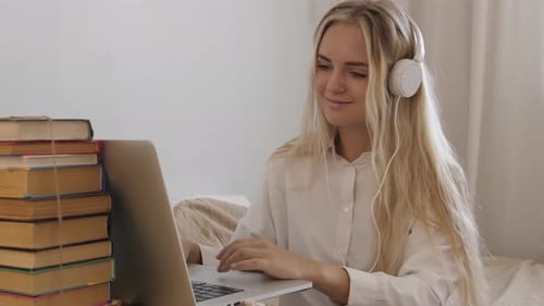 Woman with Headphones Uses Laptop at Home