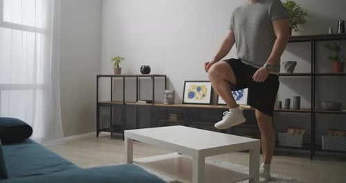Athletic Man Is Training in Apartment Standing on Table in Living Room for Legs Muscles Home Gym