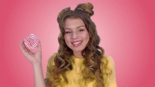 Smiling Woman Holding Donut on Pink Background