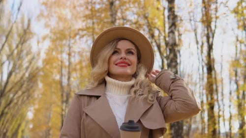 Smiling Happy Cheerful Woman Stands in Autumn Park Away Dreaming