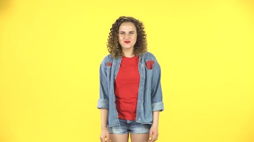 Curly Female Making a Rock Gesture, Enjoying Life and Laughing on Yellow Background at Studio