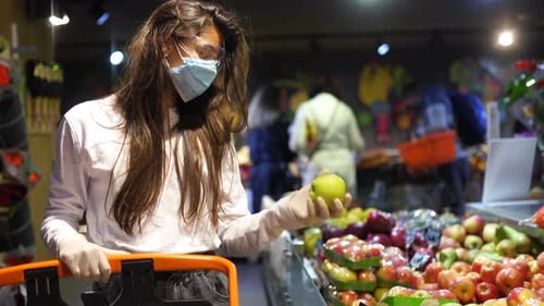Woman with the Surgical Mask and the Gloves Is Shopping in the Supermarket