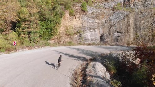 Woman cyclist riding on road bicycle on mountain road.