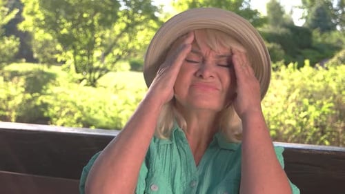 Senior Woman Massaging Head in Pain Outdoors