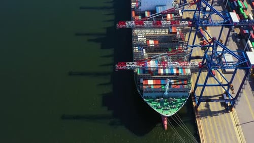 Container ship in export and import business and logistics. Shipping cargo to harbor by crane. Water